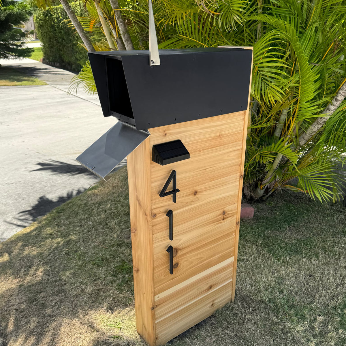 A modern mailbox with illuminated address numbers standing at the end of a long driveway
