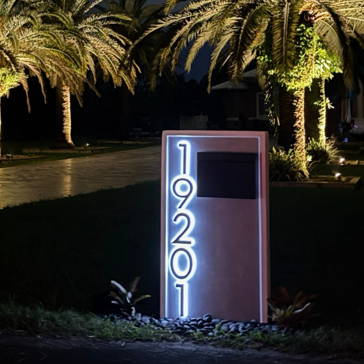 A halo-lit house number backlighting a slate mailbox after dark