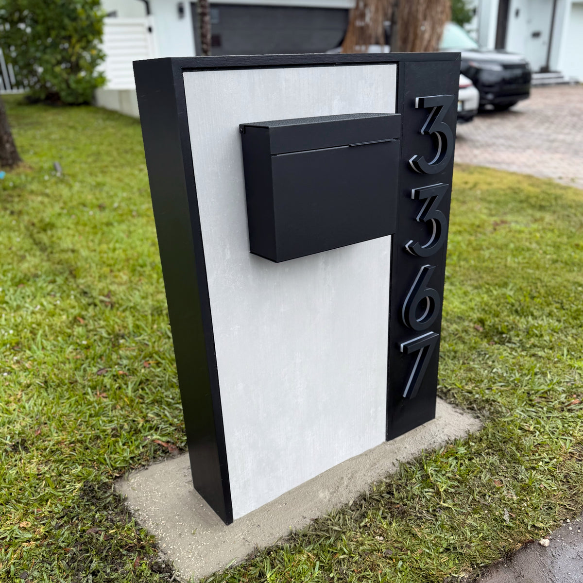 A slate-finish LED address plaque mounted on an entry wall, backlit at dusk