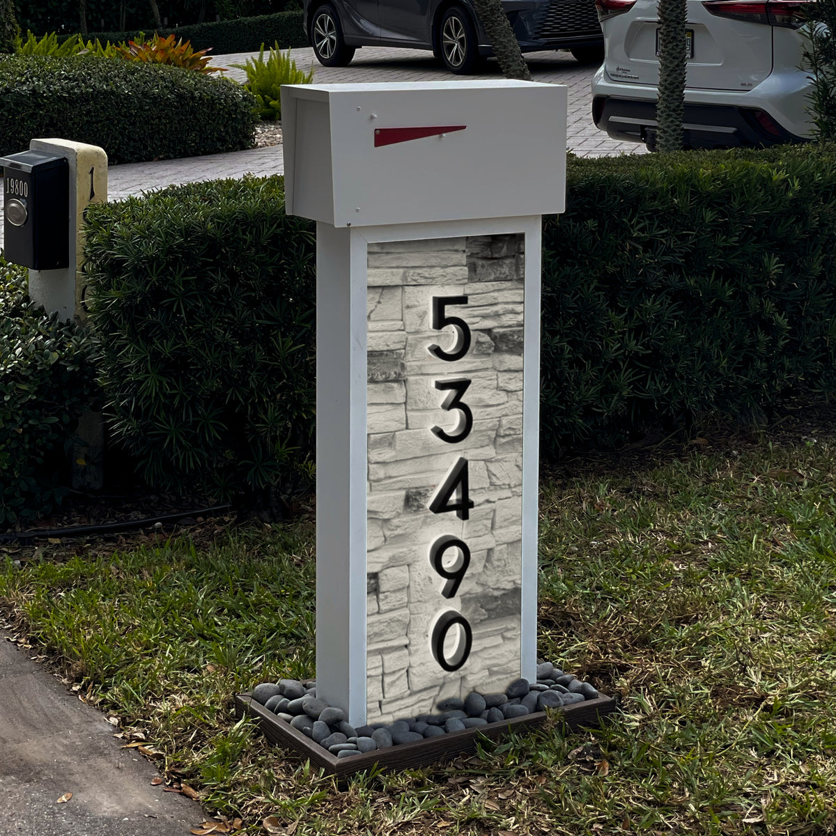 A faux pillar mailbox with an integrated locking box at a residential curb