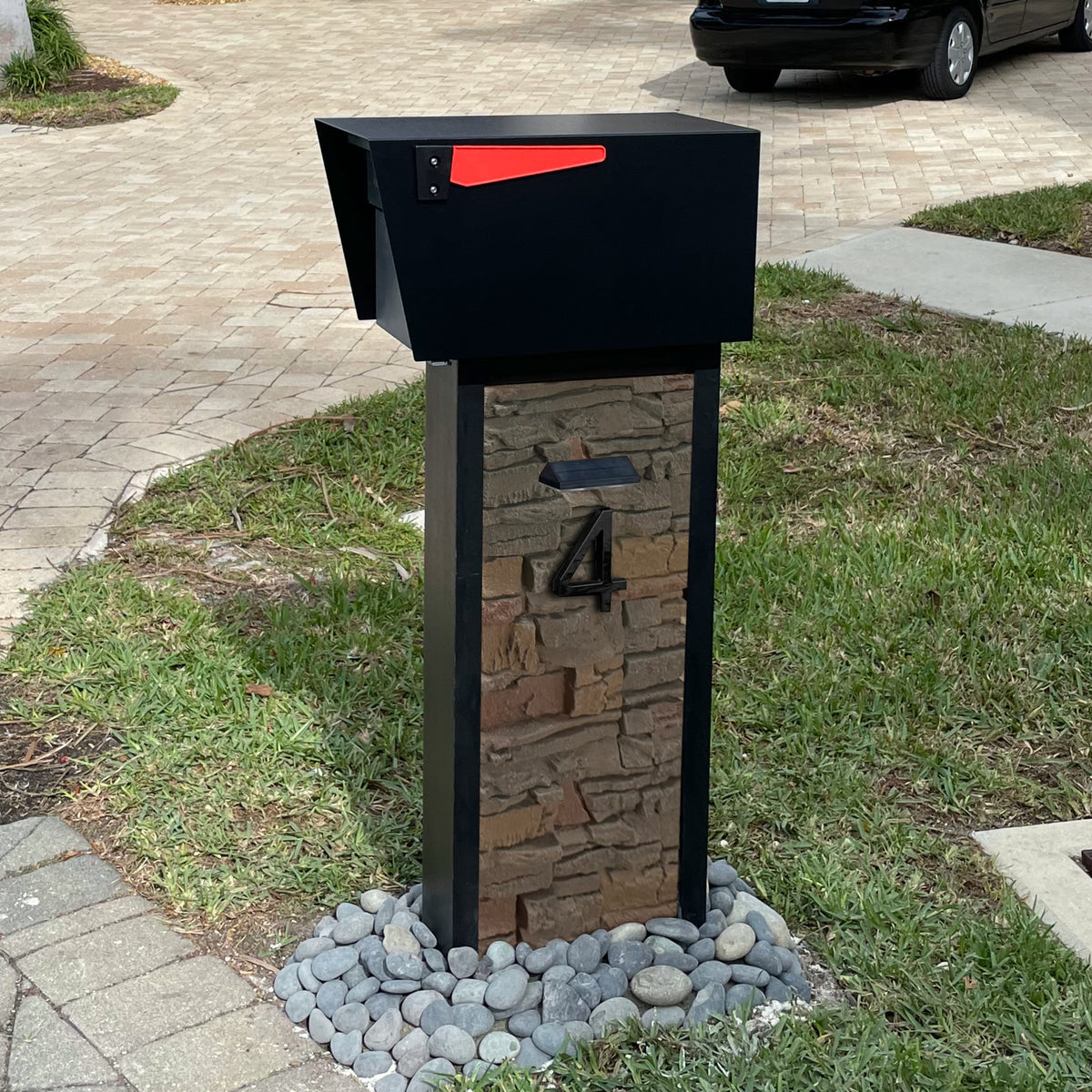 A white faux marble pillar mailbox at the end of a residential driveway