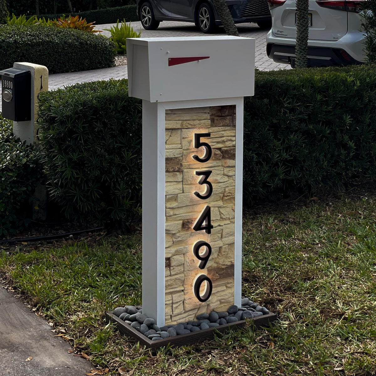 A stucco-textured column mailbox at the curb of a Mediterranean-style home