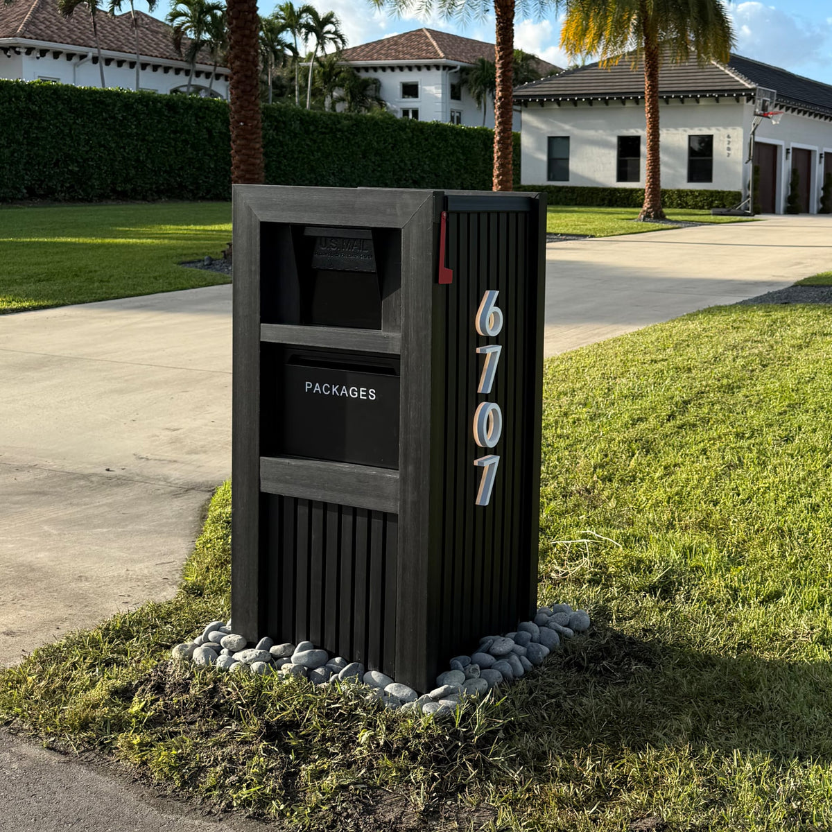 A tall black package vault mailbox standing at the curb of a residential home